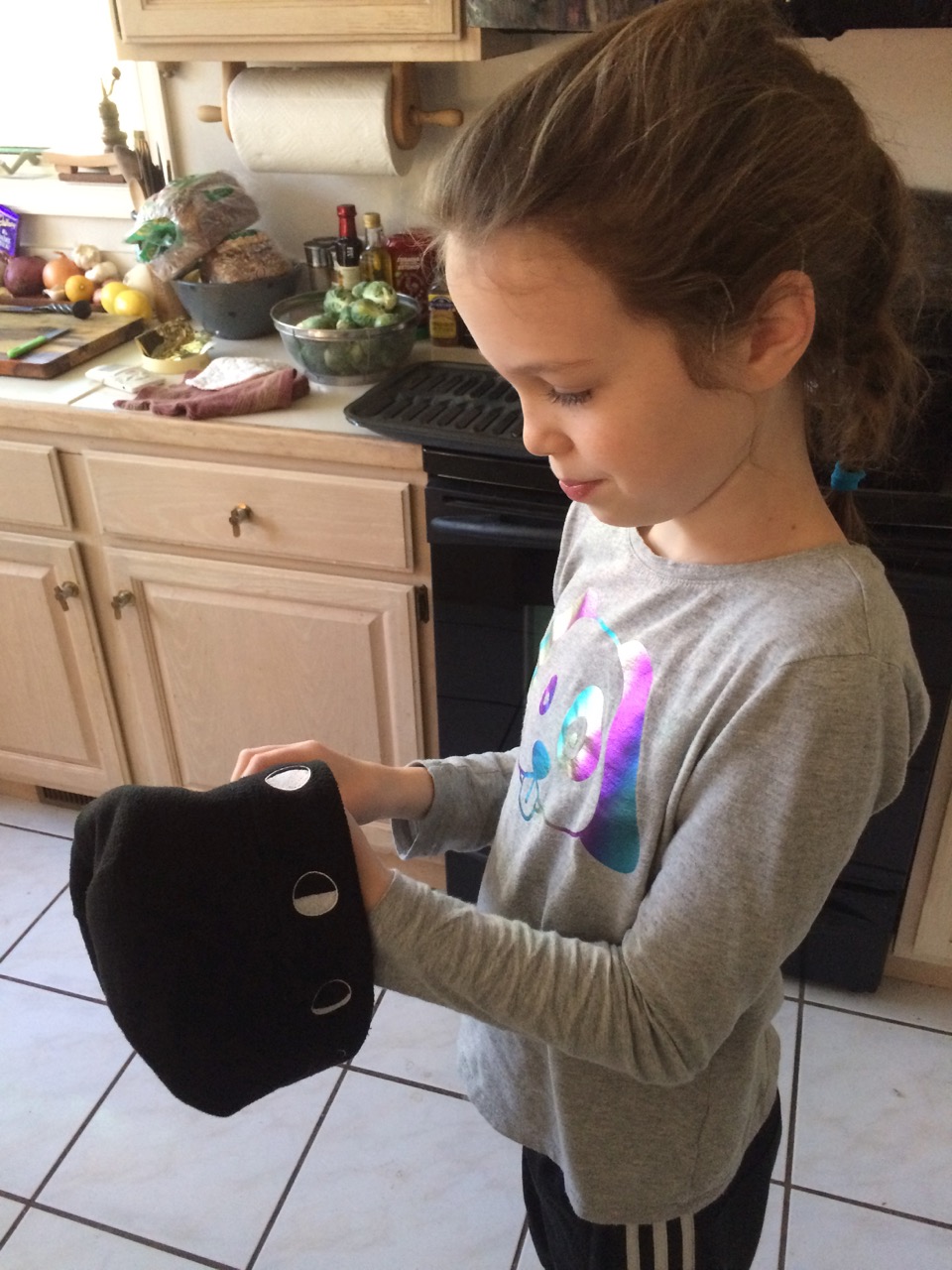 Girl holding Moon Hat in hands in kitchen