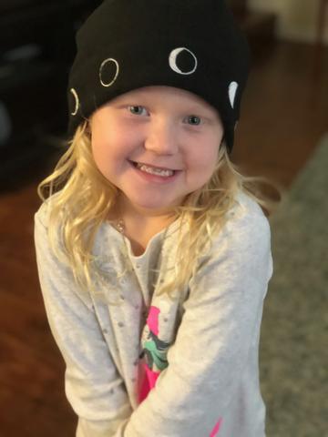 Little blond girl in Moon Hat inside house